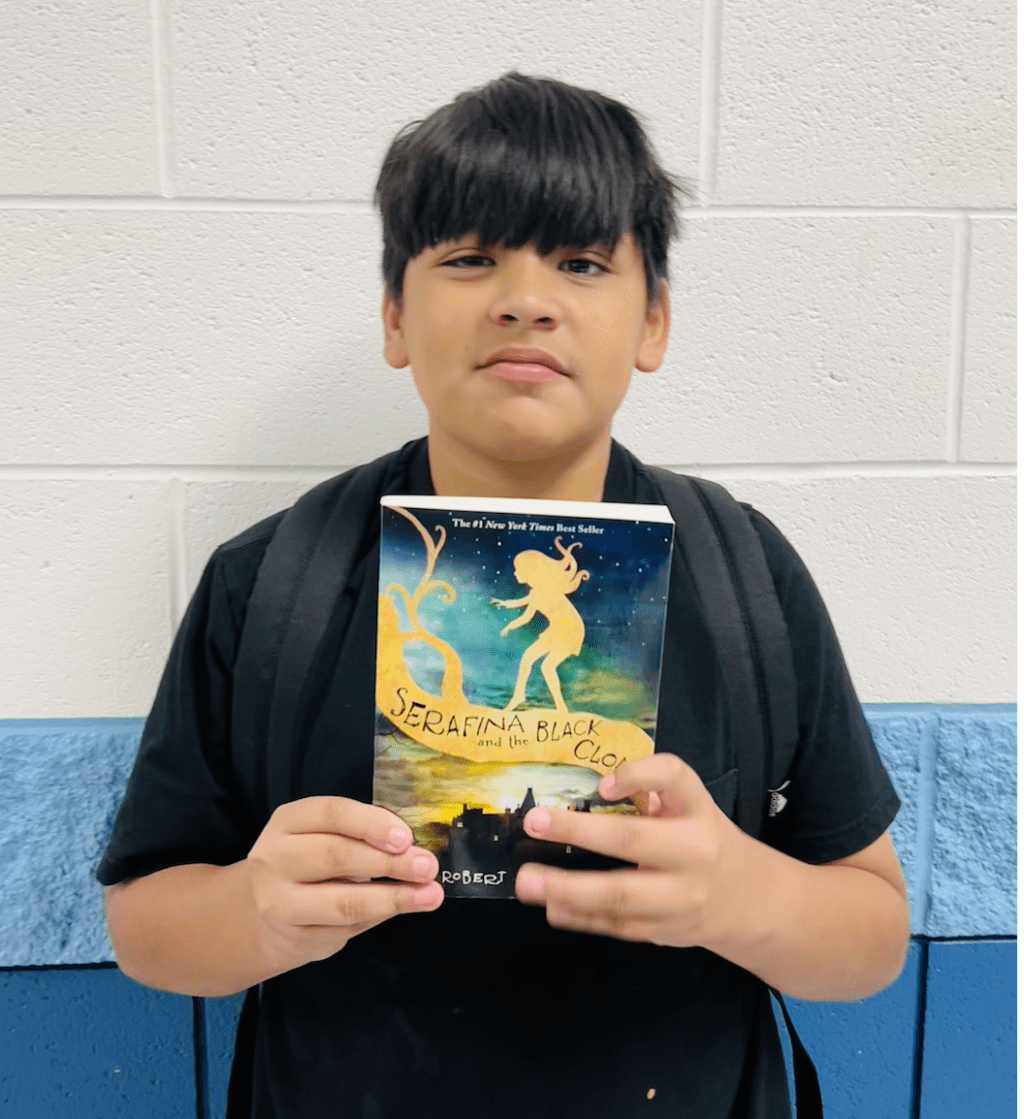 student holding a book received for earning a  praise award